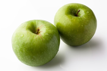 Two green fresh ripe apples on white background with reflection from high angle