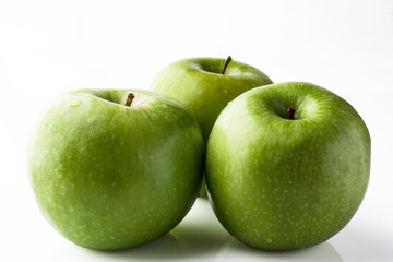 Three green apples on white background from side 