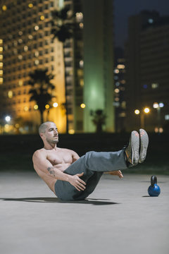 Topless Man Doing Stomach Crunches Outside At Night