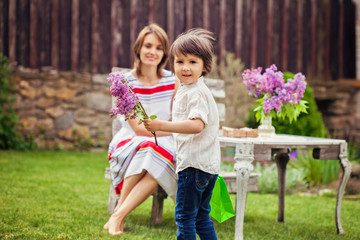 Beautiful mom, having coffee in a backyard, young cute child giv