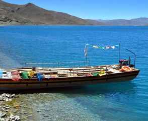 Tibet - Gebetsfahnen auf einem Boot am Blauen See