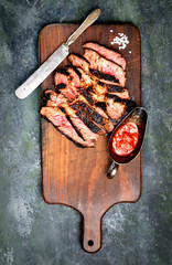 Sliced grilled Beef steak with knife and fork for meat on wooden cutting board
