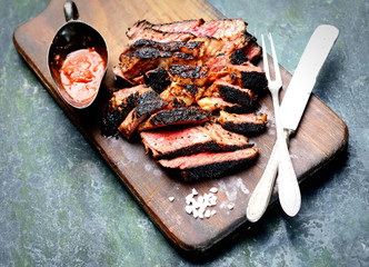 Sliced grilled Beef steak with knife and fork for meat on wooden cutting board
