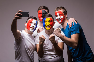 Group of football fans of their national team taking selfie photo on grey background. European 2016...