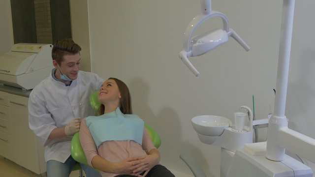 Dentist is Talking to a Woman Friendly Happy Client is Smiling Lying on a Chair Young Blond Doctor and a Patient Dental Clinic Examination of a Teeth