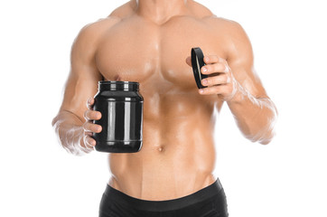 Bodybuilding and Sports theme: handsome strong bodybuilder holding a plastic jar with a dry protein and showing gesture isolated on white background in studio