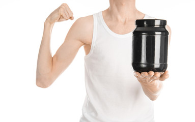 Bodybuilding and Sports theme: a thin man in a white T-shirt and jeans holding a plastic jar with a protein isolated on a white background in studio