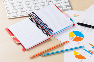 Office desk workplace with pc, charts and notepad