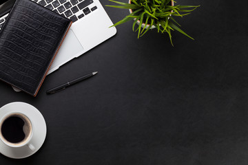 Office desk with laptop, coffee, notepad and plant