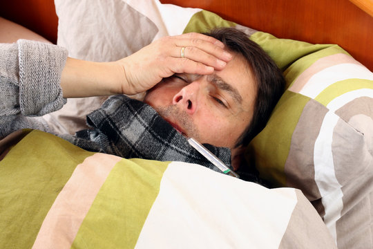 Kranker im Bett f&uuml;hlt sich sehr schlecht, Kopfschmerz