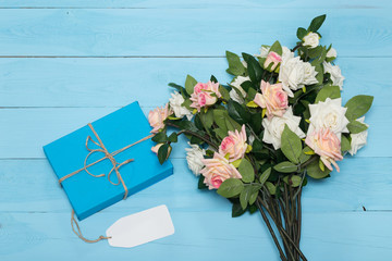 blank card, flowers and gift on a wooden blue background