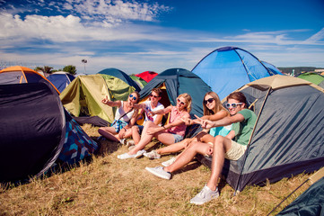 Teenagers sitting on the ground in front of tents