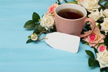 cup of tea, bouquet, roses, card on wooden background