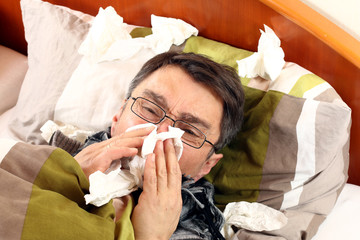 Kranker im Bett fühlt sich sehr schlecht, Kopfschmerz