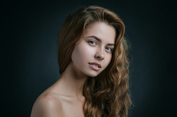 Dramatic portrait of a girl theme: portrait of a beautiful girl with flying hair in the wind against a background in studio