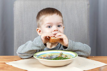 Little child bites off piece of bread at dinner