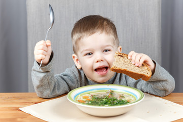 Funny little kid with plate of soup for dinner