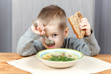 Little boy eating soup for dinner