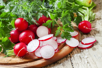 Fresh radishes, herbs, on the old wooden background, selective f