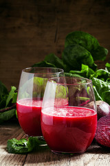 Beetroot smoothie in a large glass, fresh beets with tops, old w