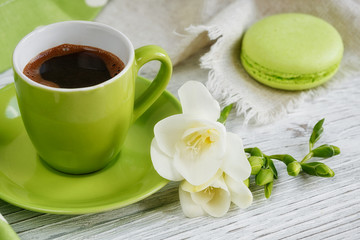 Fototapeta na wymiar Cup of black coffee, white freesia flowers and sweet pastel fren
