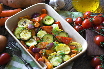 Roasted vegetables with olive oil on wooden background
