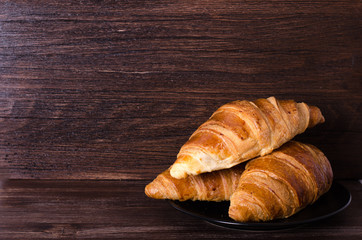 Fresh croissants on wooden background. Free space for your text.