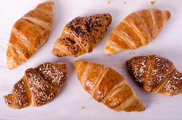 Fresh croissants on white wooden background. Free space for your text.