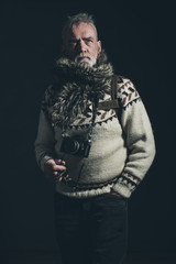 Vintage old mountaineer with knitted sweater, fur collar and SLR