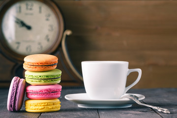 Cup of coffee and french macaron on an old wooden table.