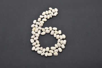 Fototapeta na wymiar Number six made from white beans on black background. Food vegan