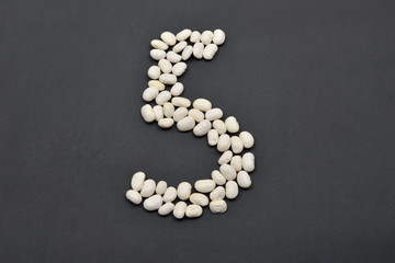 Fototapeta na wymiar Number five made from white beans on black background. Food vega