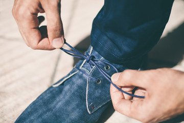 Man's hands tying shoelace of his blue shoes, Close up