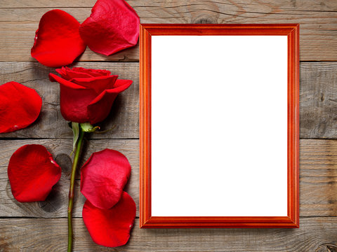 Red rose and photo frame on wooden background