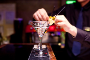 The bartender decorates stemware with martini