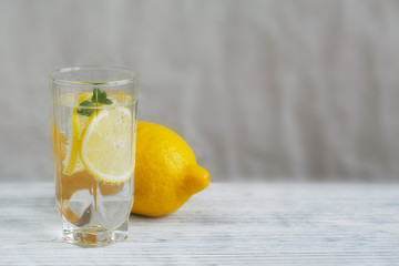 Lemonade with fresh lemon on wooden background