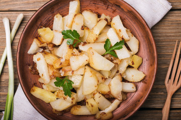 Fried potatoes with parsley and onion in an earthenware dish