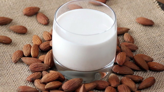Rotating Almond milk in glass, with almonds