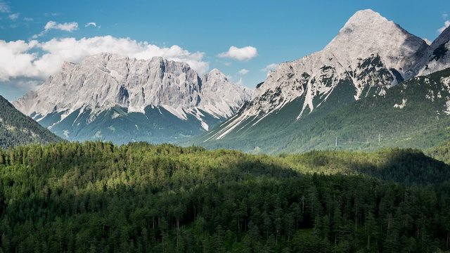 Zugspitze mountains with flowing clouds over the forest. Blindsee. Timelapse HD