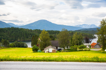 House on the shore against the backdrop of snowy mountains .