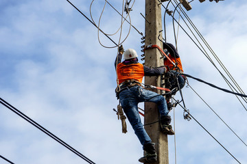 Electrician lineman repairman worker at climbing work on electric post power pole, Thai language...