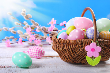 easter background  with painted eggs in wicker basket against bl