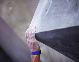 Closeup of man's hand on handhold on artificial climbing wall, hand in focus