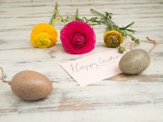 Blumen und Ostereier auf einem weißen Holzhintergrund mit der Textnachricht Happy easter