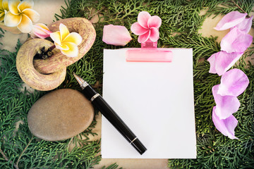 Blank paper note and pen with flowers and green leaf