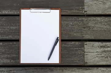 Blank white paper sheet on clipboard with black pen on wood floor background