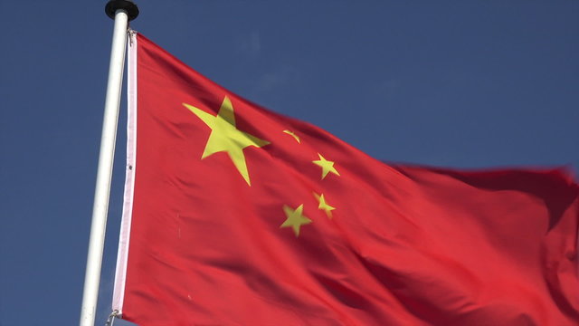 Chinese flag blowing in wind with blue sky background, China