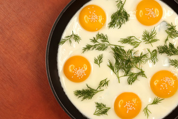 pan on the table with fried scrambled eggs with dill and sesame