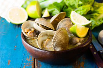 Seafood soup of clams in clay bowl on wooden blue background. Mariscal or paila marina