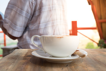 close up a coffee cup on wood table morning light